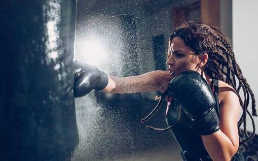 Female Kickboxer on punching bag